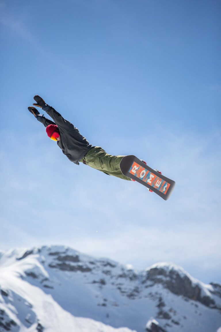 Dynamic snowboarder capturing airtime against snowy mountain backdrop in Morzine, France.