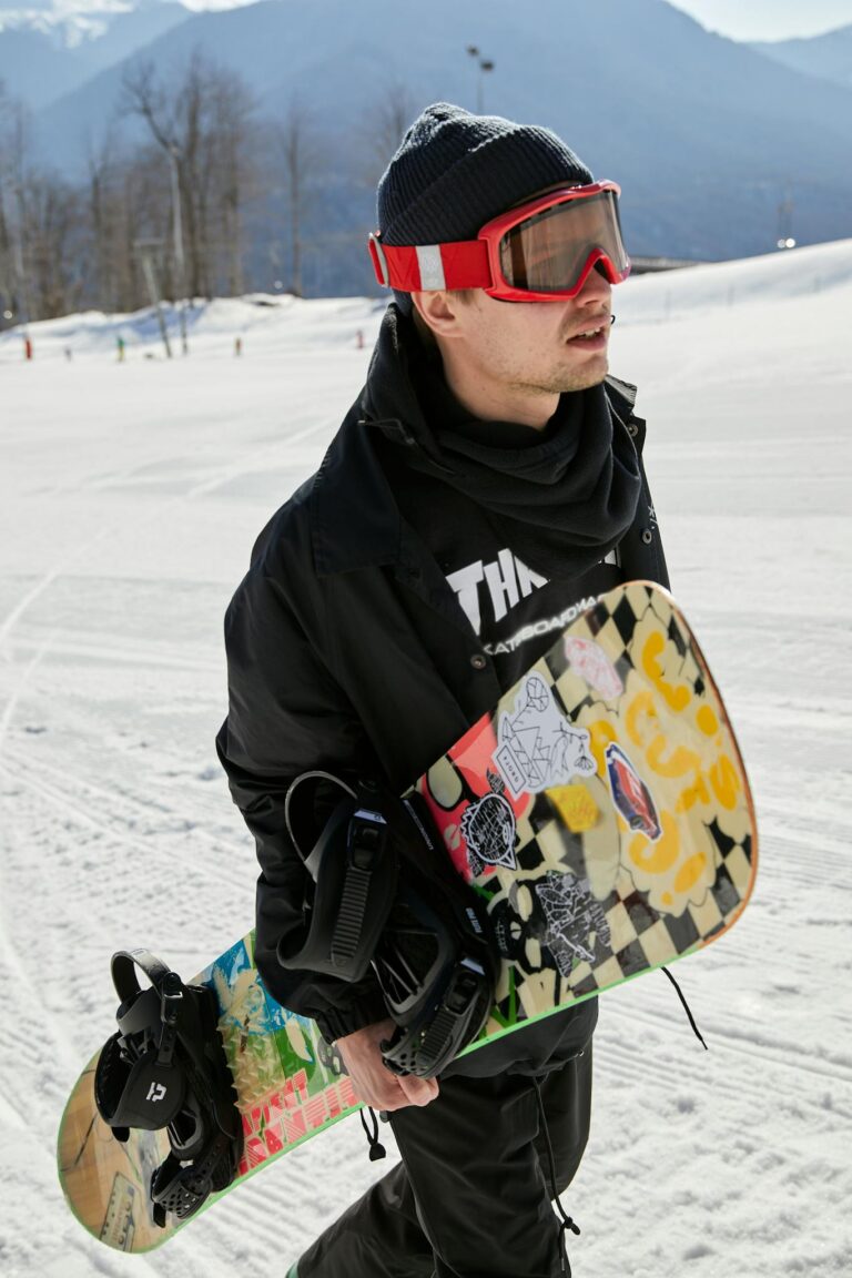 Snowboarder walking on snow with mountain backdrop, enjoying winter sports.